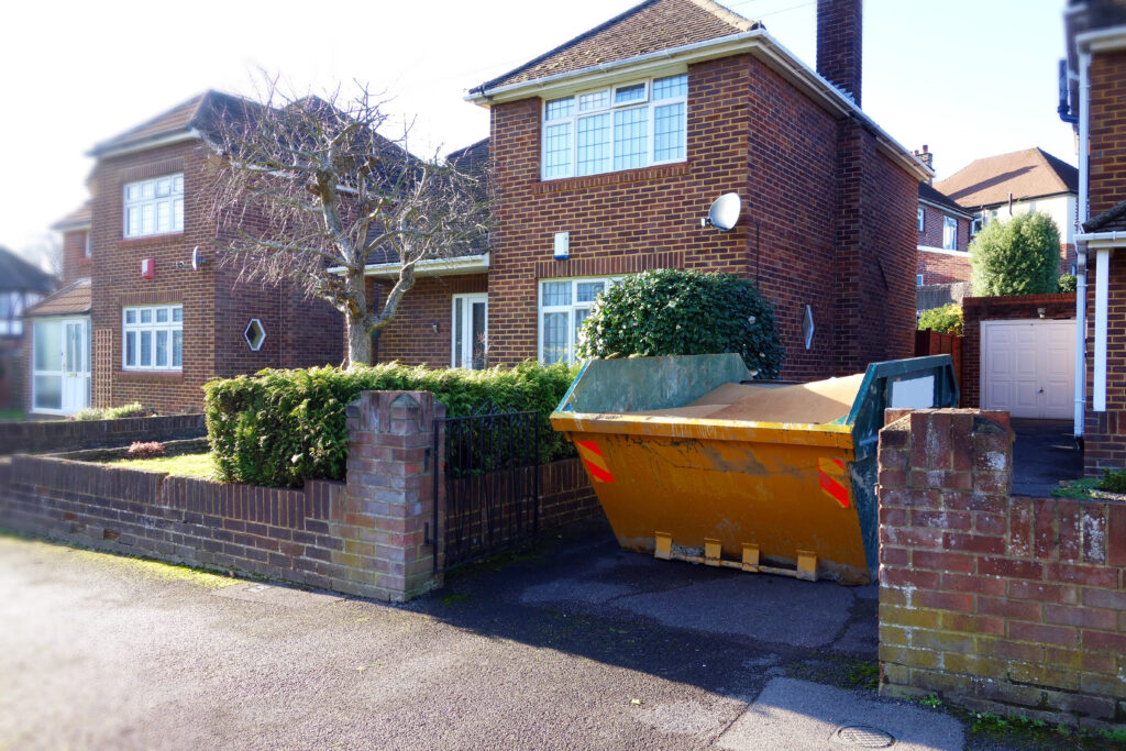 An image of a yellow skip in the driveway of a house.