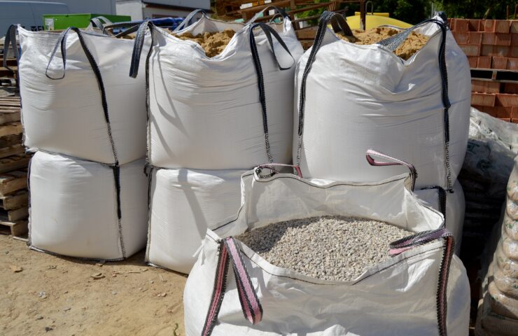 Seven large white bags filled with aggregate, stacked on eachother.